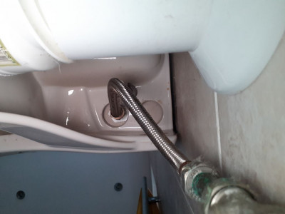 Supply from underneath showing issue with offset plastic nut against access hole in toilet bowl.