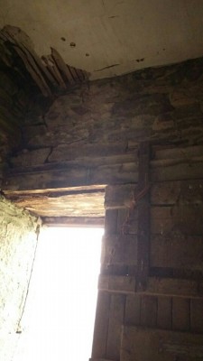 Internal view of stone wall above wooden lintel.